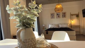 Habitación de hotel con cama, mesita de noche y un florero decorativo sobre un camino de mesa tejido.