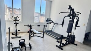 Un gimnasio con cinta de correr, banco de pesas y diversos equipos de ejercicio.