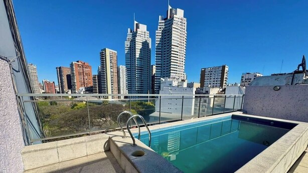 Una piscina en la azotea con vistas a un horizonte urbano, rodeada de rascacielos.