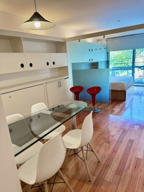 Een moderne keuken met witte kasten, een glazen eettafel en rode barstoelen.