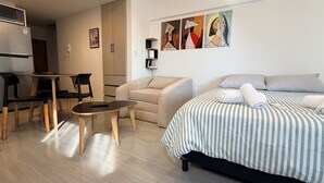 A modern hotel room with a bed, a sofa, a dining table, and chairs. There are abstract paintings on the wall. - Palermo Portẽnito: A Cosmopolitan Nomad Oasis (Buenos Aires)