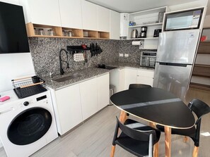 Eine kleine Küche mit Waschmaschine, Mikrowelle und Kühlschrank.