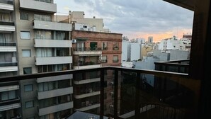 Un balcone con tavolo e sedie, vista su un paesaggio urbano con diversi edifici.