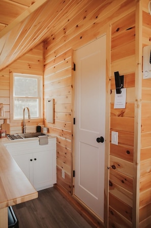 A compact kitchen with a sink, cabinets, and a door with a WiFi sign.