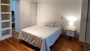 A bedroom with a bed, a nightstand, a wardrobe, and a built-in shelf unit. - Palermo Soho getaway. Pool,  sauna and workspace (Buenos Aires)