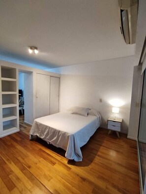 Ein Schlafzimmer mit Bett, Nachttisch, Kleiderschrank und einem eingebauten Regal.
