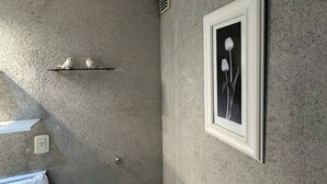 A bathroom with a textured wall, a framed picture, a towel rack, and a light switch. - Palermo Soho getaway. Pool,  sauna and workspace (Buenos Aires)