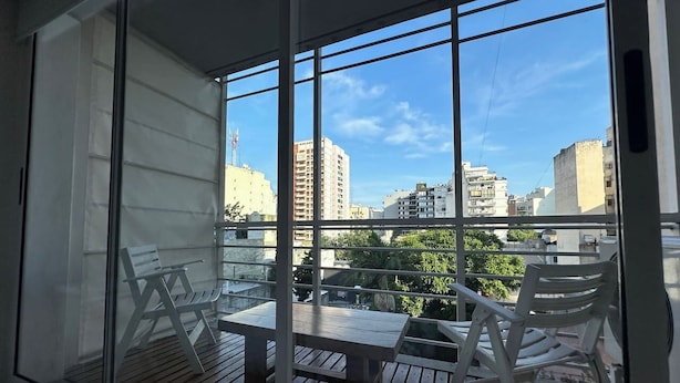 A balcony with a table and chairs, a view of the cityscape, and a clear sky. - Palermo Soho getaway. Pool,  sauna and workspace (Buenos Aires)