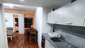 A modern kitchen with a granite countertop, white cabinets, and a wooden floor. - Palermo Soho getaway. Pool,  sauna and workspace (Buenos Aires)