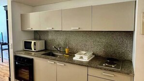 Una cocina moderna con microondas, estufa, horno y encimera de granito.