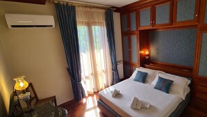 Quarto de hotel com cama, mesa de cabeceira com abajur e guarda-roupa.