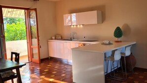 Uma cozinha compacta com ilha central, pia e um pequeno espaço bar com banquetas.