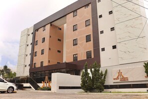 A multi-story hotel with a modern design, featuring a prominent entrance with a staircase and a large sign. - Mont Cristo #401 - Beachfront por Carpediem (João Pessoa)