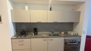 Eine kompakte Küche mit Granitarbeitsplatte, einem eingebauten Backofen und einem Spülbecken.