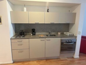 A compact kitchen with a granite countertop, a built-in oven, and a sink. - Palermo Soho: Sleek flat with stunning view (Buenos Aires)