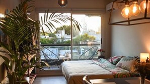 Una camera da letto accogliente con un letto, un tavolo da pranzo, sedie, una pianta in vaso e un balcone con vista.