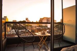 Een balkon met twee stoelen, een tafel en een theepot.