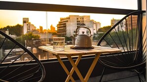 Un balcone con un tavolo, un bollitore e un bicchiere d'acqua.