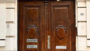 A double wooden door with a semi-circular arch above, set in a building with white and green trim. - Grand Rivadavia: 3-BR Ensuite High Ceiling Home (Buenos Aires)