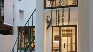 A multi-level apartment with a staircase, a potted plant, and a view of the interior through a glass door. - Grand Rivadavia: 3-BR Ensuite High Ceiling Home (Buenos Aires)