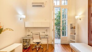 A compact, well-lit room with a wooden floor, a desk with a chair, a bookshelf, and a door leading to an outdoor area. - Grand Rivadavia: 3-BR Ensuite High Ceiling Home (Buenos Aires)