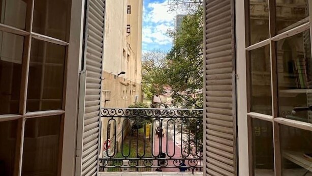 An open balcony with a view of a tall building and a clear sky. - Grand Rivadavia: 3-BR Ensuite High Ceiling Home (Buenos Aires)