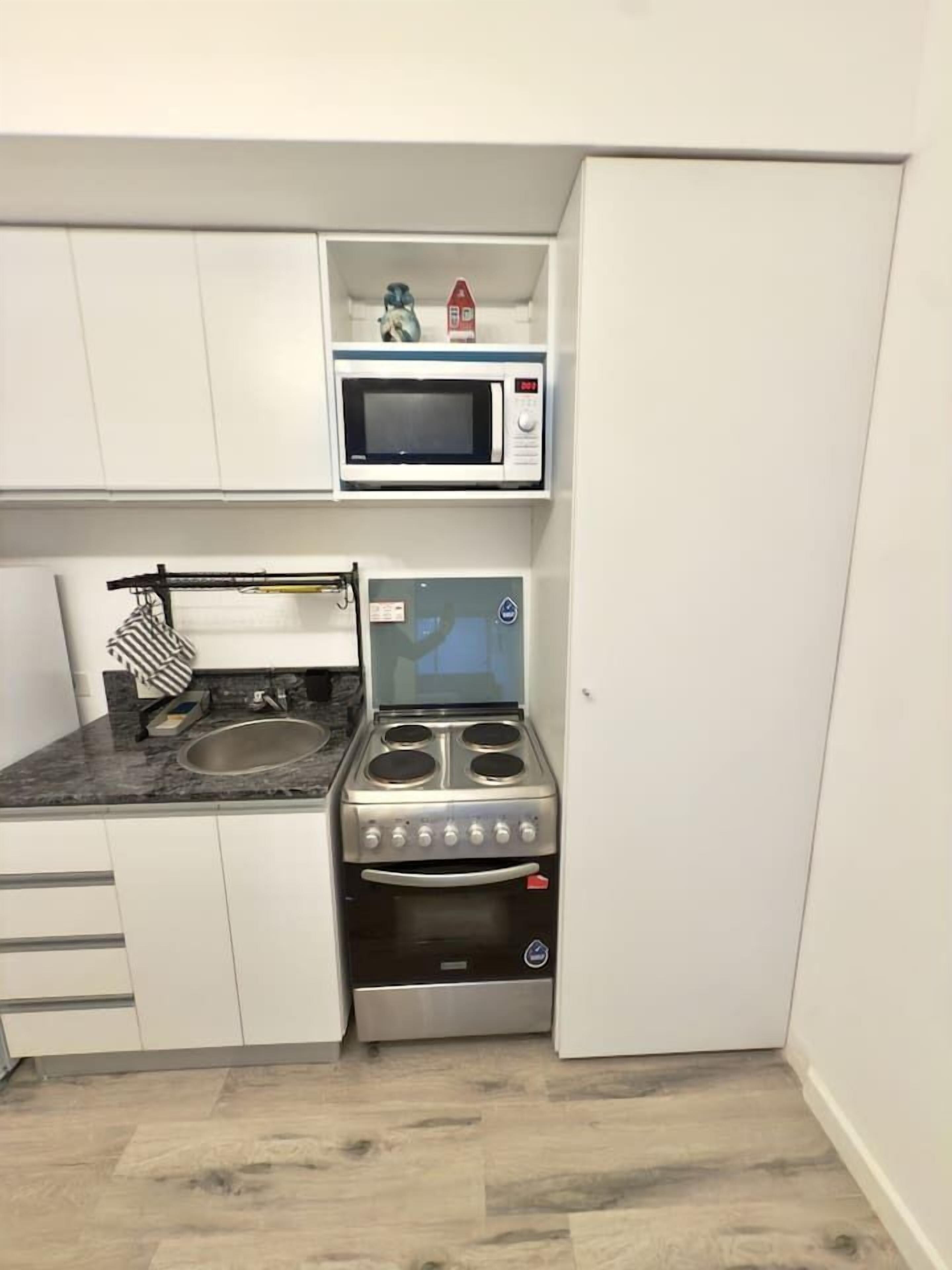 A compact kitchen with a microwave, stove, and sink.