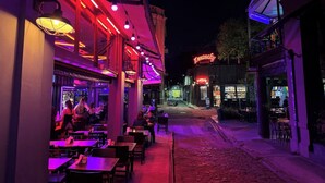 An outdoor dining area with tables and chairs, illuminated by string lights. - Plaza Serrano Front Row Loft by airesB&B (Buenos Aires)