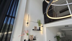A modern kitchen with a dining area, featuring a black countertop, white cabinets, and a hanging light fixture. - Plaza Serrano Front Row Loft by airesB&B (Buenos Aires)
