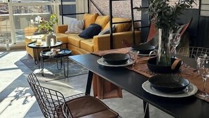 Zona pranzo moderna con tavolo nero, sedie in metallo e un vaso di fiori.