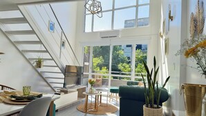 A modern living room with a staircase, large windows, and a view of greenery outside. - Plaza Serrano: Casa Dorada luxury loft by airesB&B (Buenos Aires)