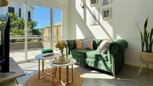 A spacious living room with a green sofa, a round coffee table, and a large window providing a view of the outdoors. - Plaza Serrano: Casa Dorada luxury loft by airesB&B (Buenos Aires)