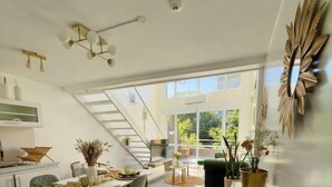 A modern kitchen with a dining area, a staircase, and large windows. - Plaza Serrano: Casa Dorada luxury loft by airesB&B (Buenos Aires)