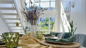 A dining area with a table set for four, a vase with dried flowers, and a staircase in the background. - Plaza Serrano: Casa Dorada luxury loft by airesB&B (Buenos Aires)