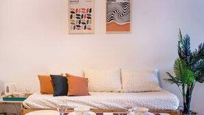 Ein modernes Wohnzimmer mit einer Couch, zwei Poufs, einem Couchtisch und einer Pflanze.