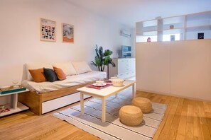 A modern living room with a sofa, a coffee table, and a plant. There is a white cabinet and a TV in the background. - Warm, quiet & inviting retreat: Steps from Palermo (Buenos Aires)