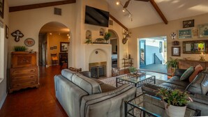 A spacious living room with leather sofas, a fireplace, and a large TV. - Triangle Ranch - Private West Texas Retreat (Alpine)