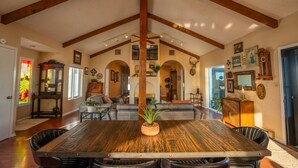 A spacious dining area with a large wooden table and chairs, a fireplace, and a high ceiling with exposed beams. - Triangle Ranch - Private West Texas Retreat (Alpine)