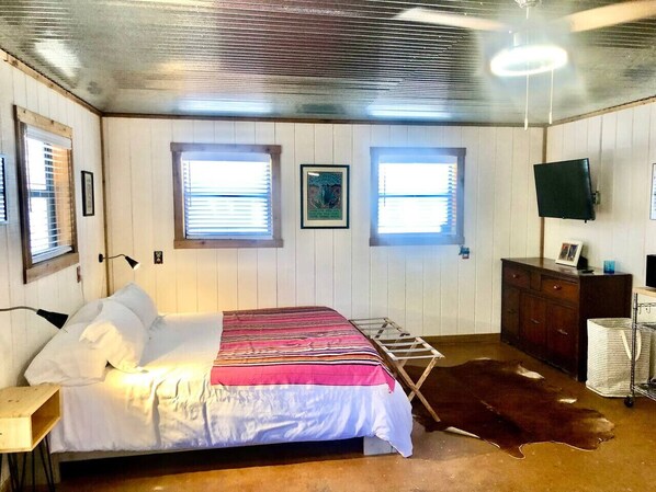 Une chambre à coucher avec un lit, une commode en bois, un téléviseur et une fenêtre.