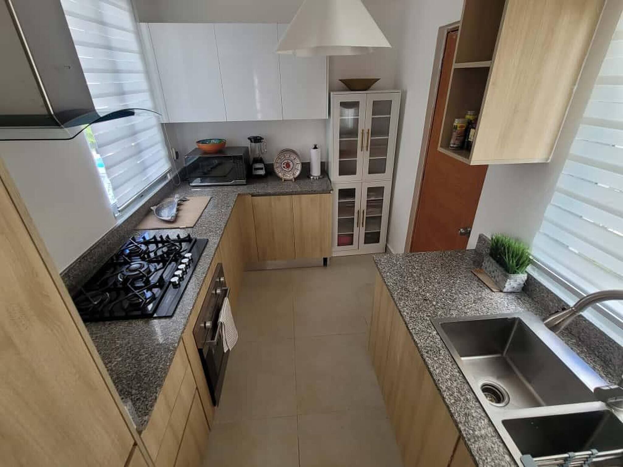 A compact kitchen with a gas stove, cabinets, a sink, and a window.