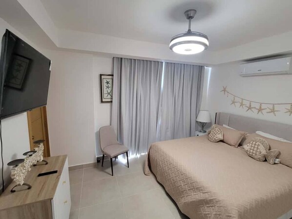 A bedroom with a bed, a chair, a desk, a TV, and a ceiling fan. - Damani Modern Pool Villa Escape (Punta Cana)