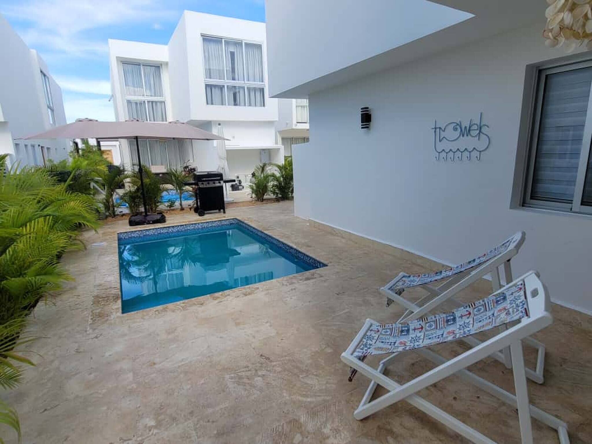 A pool area with a small pool, lounge chairs, and a barbecue grill.