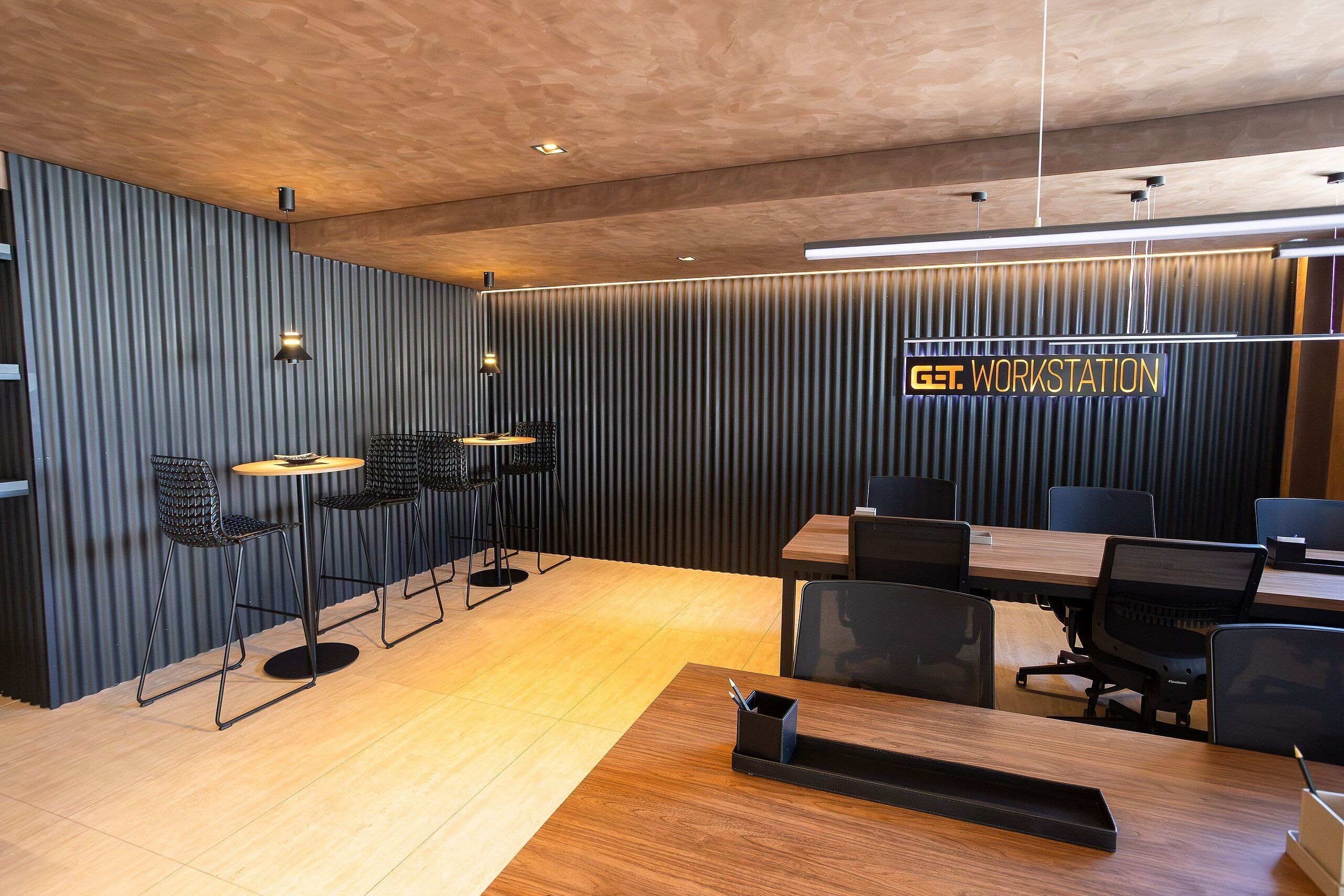 Una sala de conferencias moderna con una mesa de madera, sillas negras y un letrero que dice 'GET WORKSTATION'.