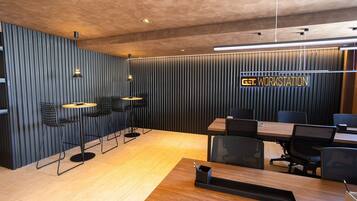 Una sala de conferencias moderna con una mesa de madera, sillas negras y un letrero que dice 'GET WORKSTATION'.