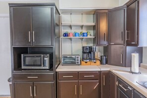 A compact kitchen with dark wooden cabinets, a microwave, a toaster, and a coffee maker.