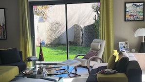 Un soggiorno moderno con una porta vetrata che dà su un giardino, un divano, una poltrona e un tavolino da caffè.