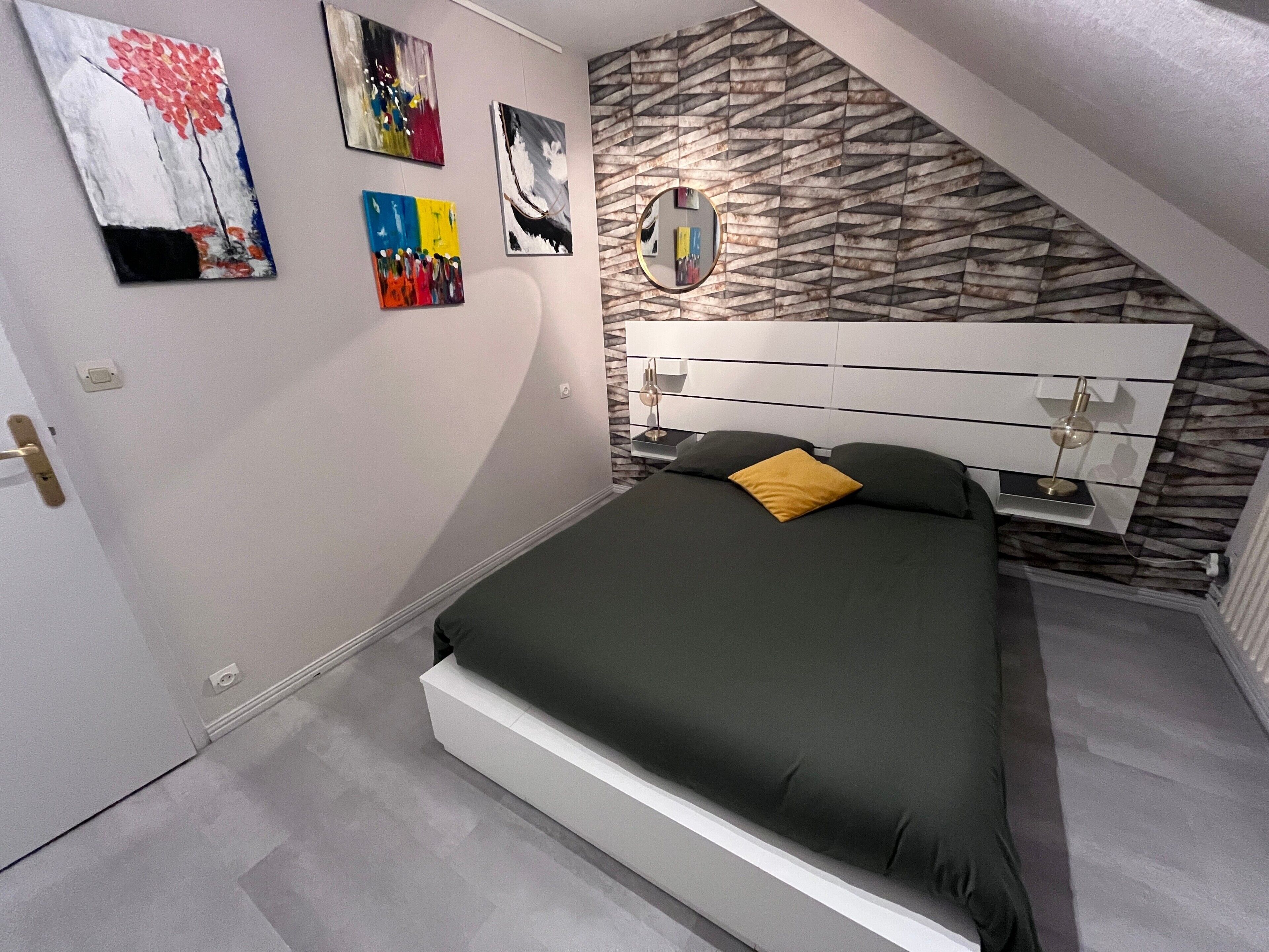Un dormitorio con cama, cómoda, espejo y decoración en la pared.