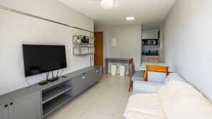 A modern living room with a flat-screen TV, grey entertainment unit, white sofa, and a small dining area with a table and chairs. - Buenos Ayres #504 - Comfortable Apartment by Carpediem (João Pessoa)