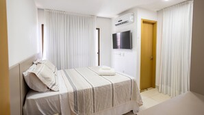 A bedroom with a bed, curtains, a TV, and an air conditioning unit. - Buenos Ayres #504 - Comfortable Apartment by Carpediem (João Pessoa)