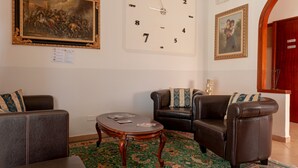 A room with a large wall clock, two leather sofas, a small wooden table, and a patterned rug. - 'Bandb Cindy - Yellow Room' with Shared Garden, Wi-Fi and Air Conditioning (Navacchio)